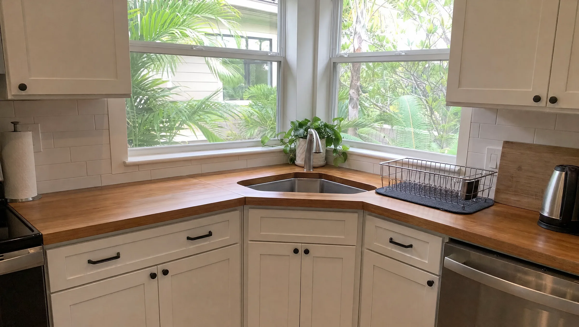 Kitchen with the sink set in the corner under two windows that meet at the corner