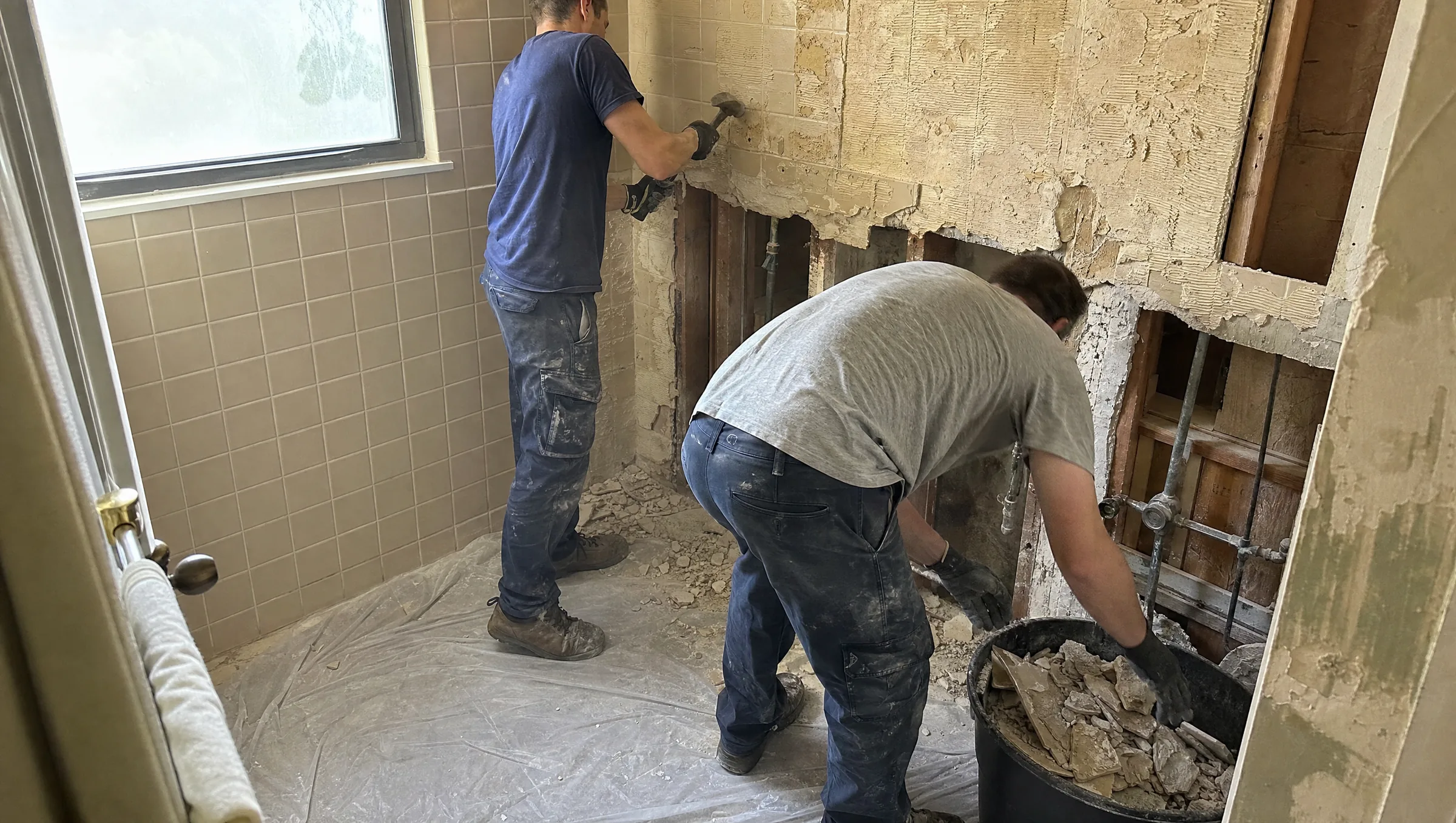Old shower tile being demolished down to the studs during a bathroom remodel