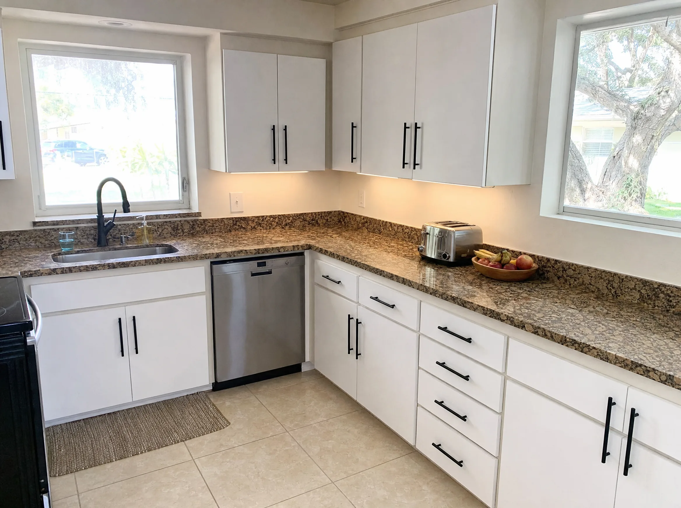 Kitchen cabinets refaced with new white flat-panel doors and modern pulls on the original cabinet boxes