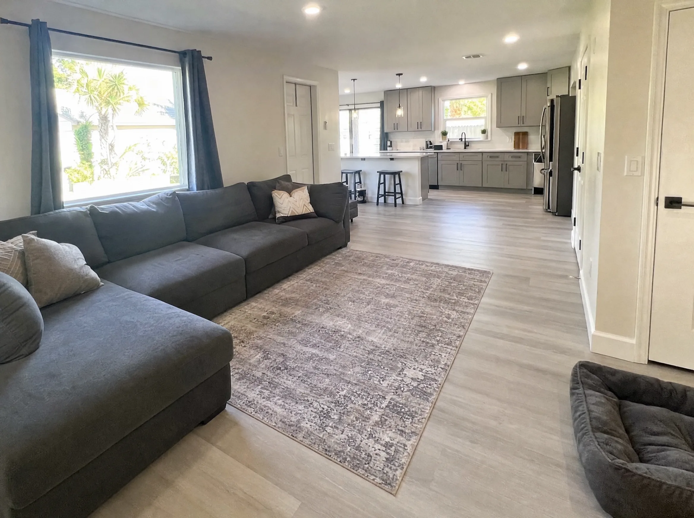 Whole-home remodel with new flooring, fresh paint, recessed lighting and an updated kitchen visible from the living room