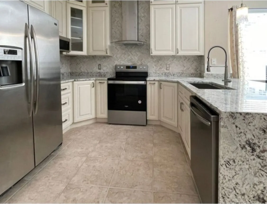 After: Kitchen after the remodel: cherry cabinets replaced with white cabinets, granite counters and new tile floor