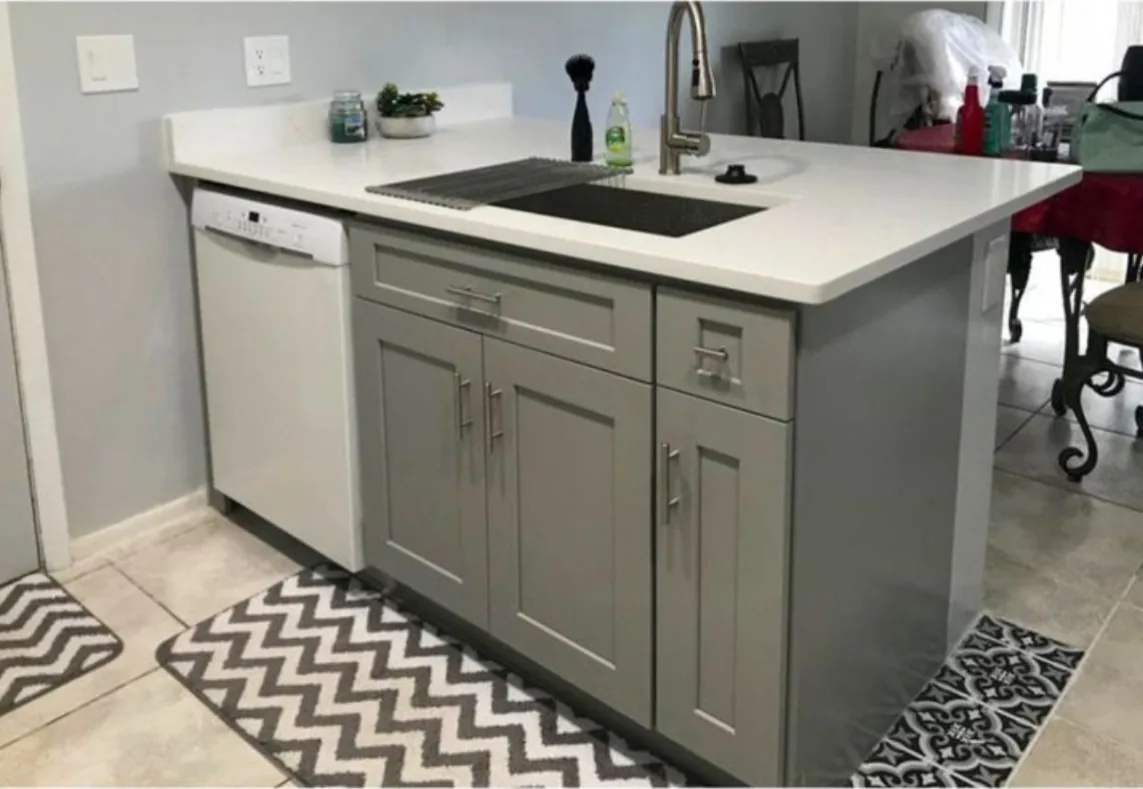 After: Kitchen after the remodel: worn white peninsula replaced with a gray shaker peninsula and white quartz top