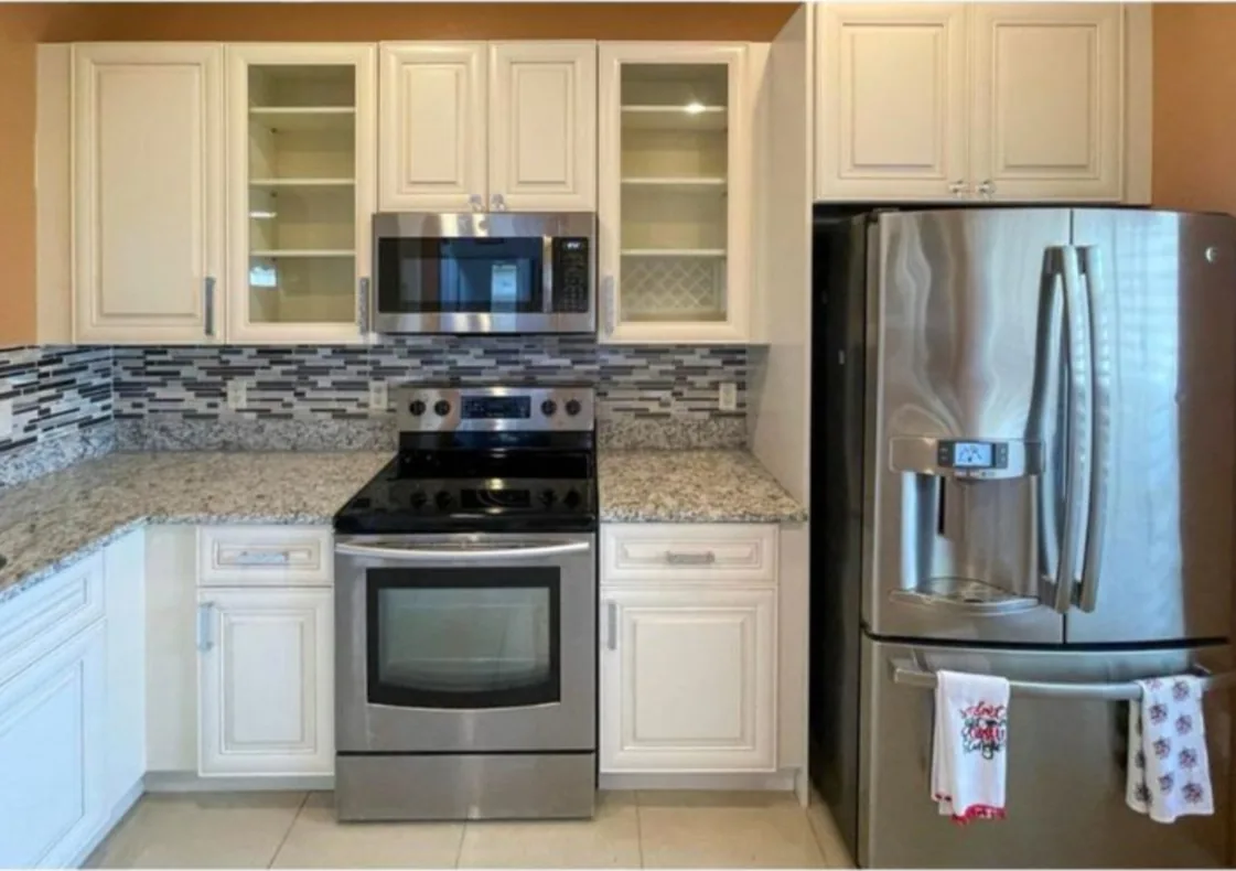 After: Kitchen after the remodel: oak cabinets replaced with white cabinets and a glass mosaic backsplash
