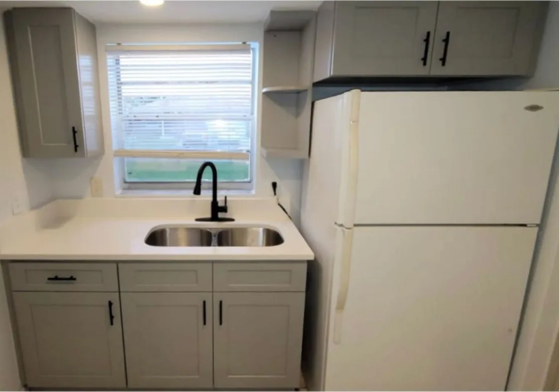 After: Kitchen after the remodel: dated white cabinets replaced with gray shaker cabinets and quartz