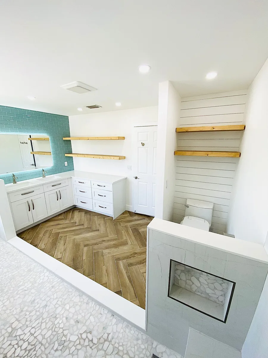 Bathroom with herringbone floor, white vanity and floating wood shelves