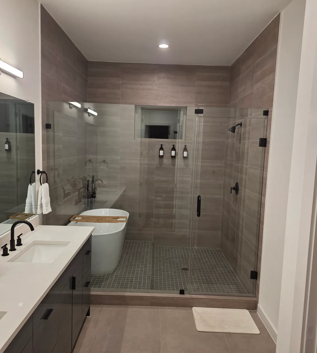 Primary bathroom with a glass walk in shower, freestanding tub and wood look wall tile