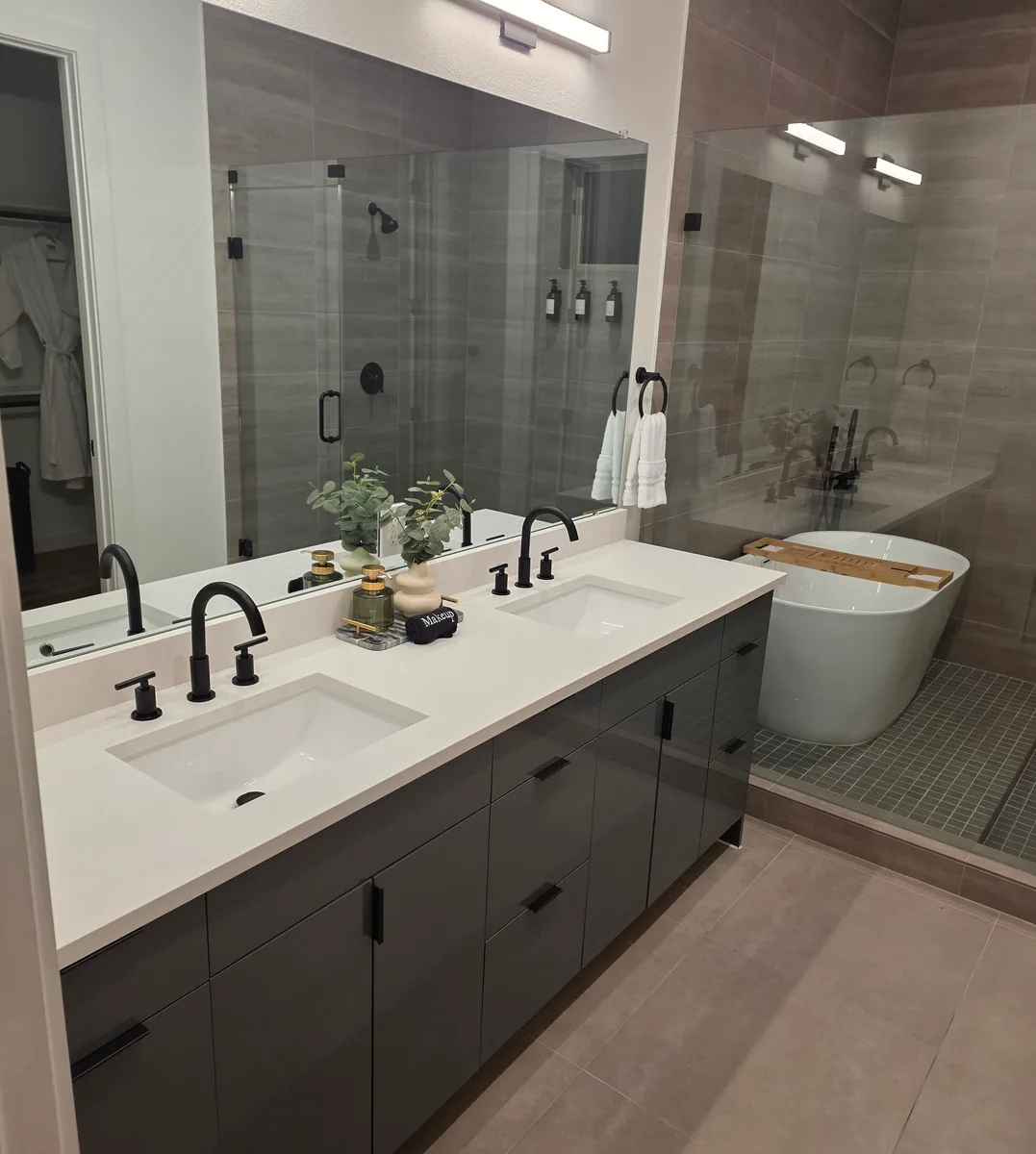 Charcoal double vanity with matte black faucets facing a glass shower and freestanding tub