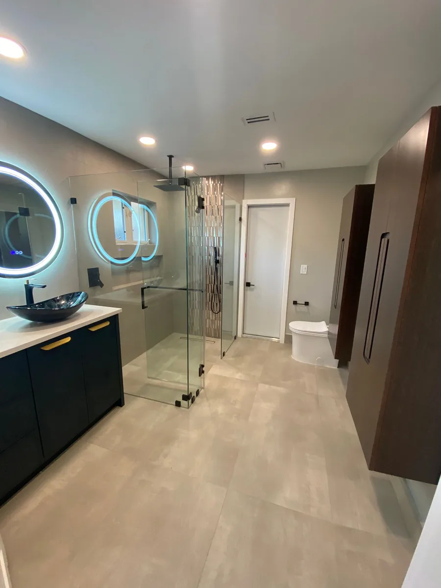 Bathroom with round LED mirrors, vessel sinks and a glass shower