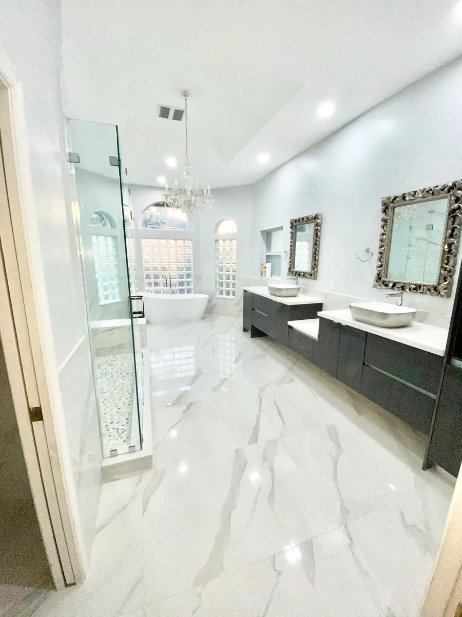 Long marble look bathroom with a floating vanity and glass shower
