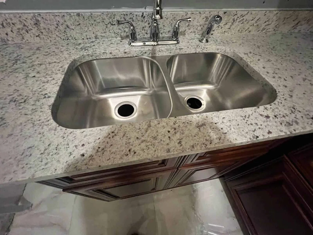 Stainless double bowl undermount sink in a white granite countertop