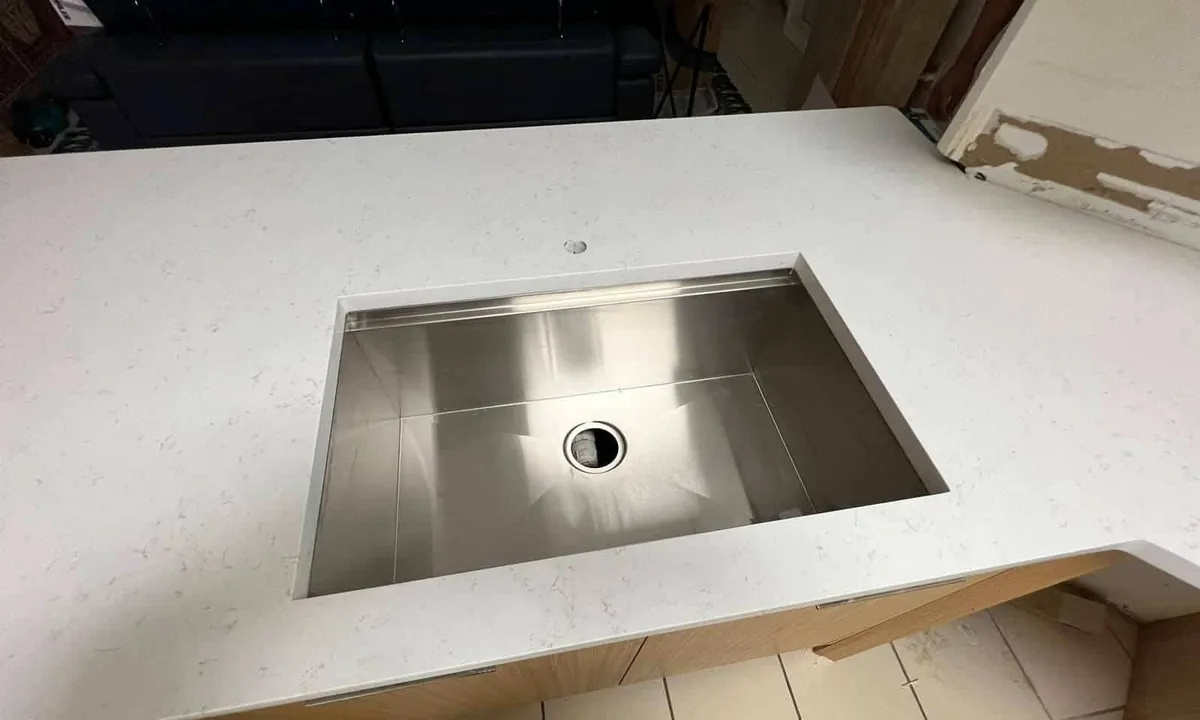 Undermount stainless sink cut into a white quartz countertop