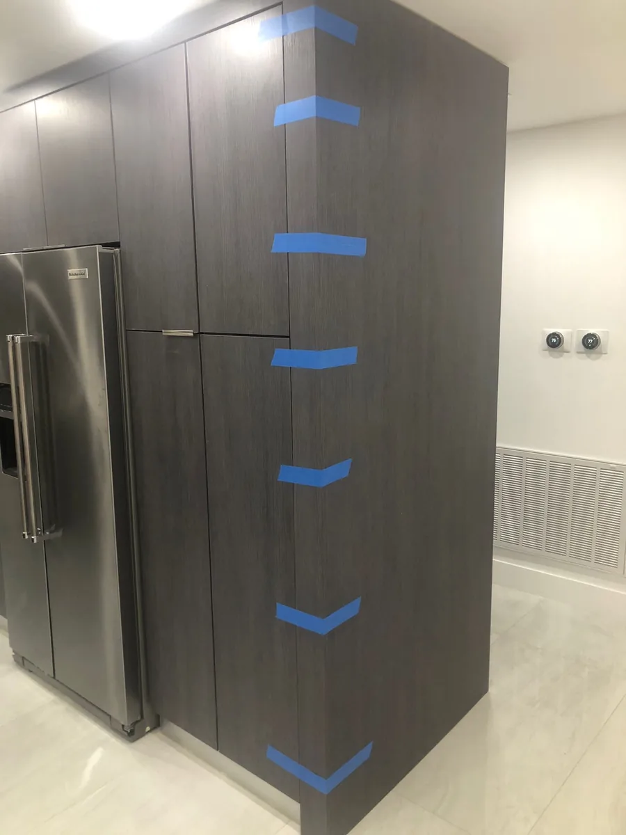 Tall wood grain cabinet panel with corner protection during installation