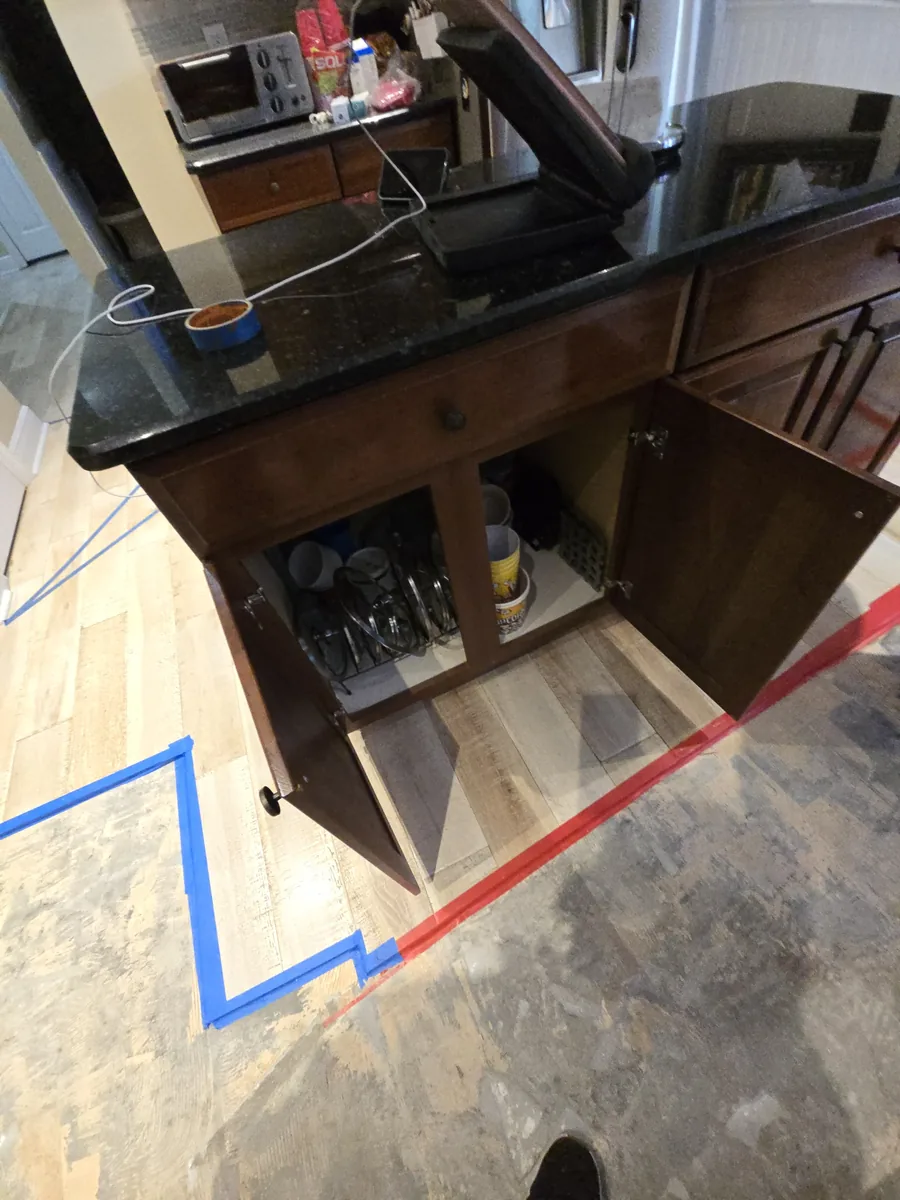 Painter tape layout lines on the floor marking the new cabinet footprint