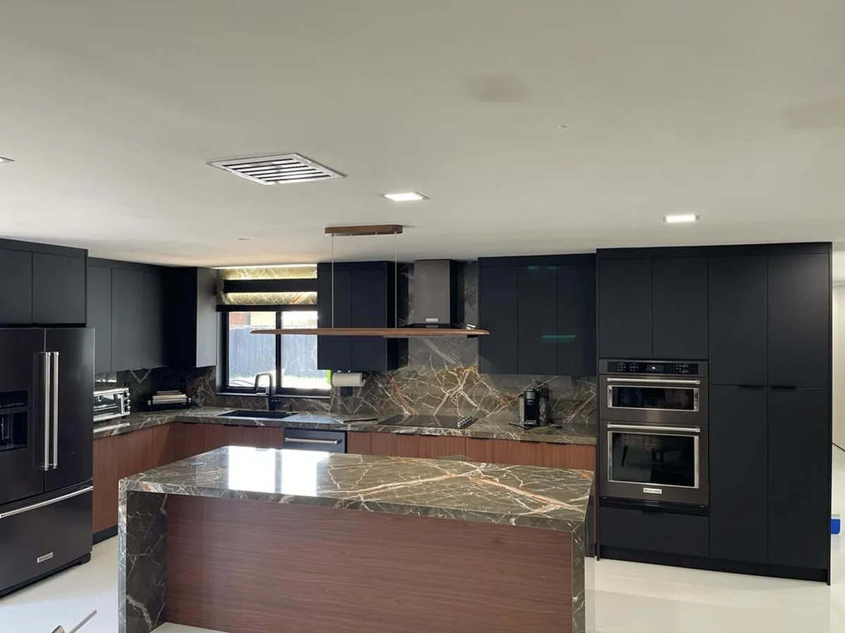 Charcoal handleless kitchen with a dramatic marble island on walnut base