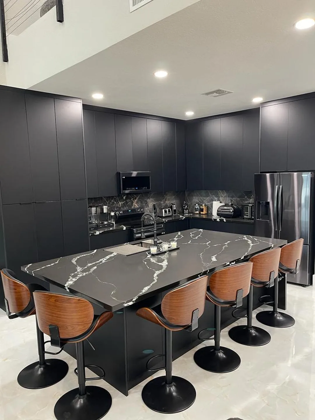 Charcoal kitchen with a black veined quartz island and a row of walnut bar stools