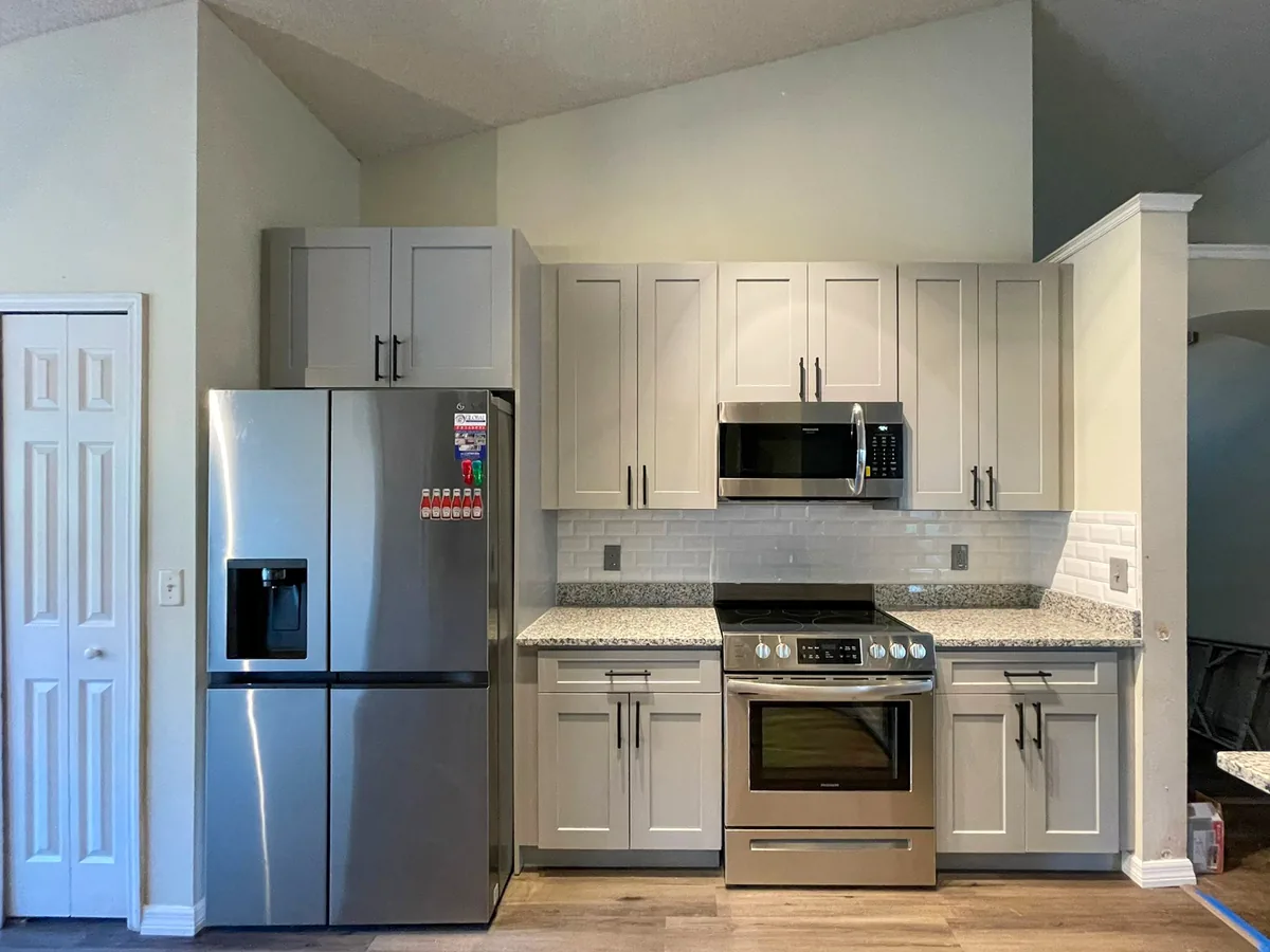 Gray shaker kitchen with stainless appliances under a vaulted ceiling