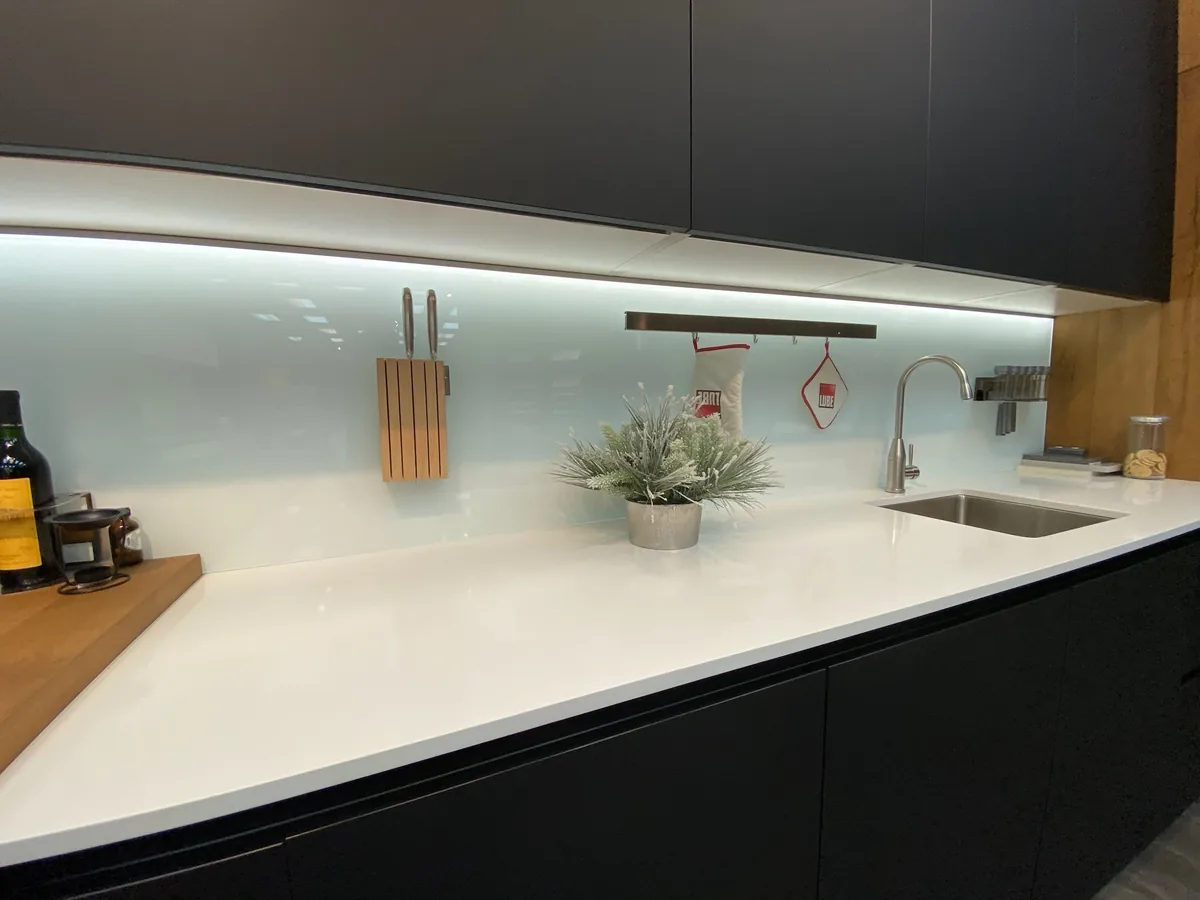Black and wood kitchen with under cabinet LED lighting and a white quartz countertop