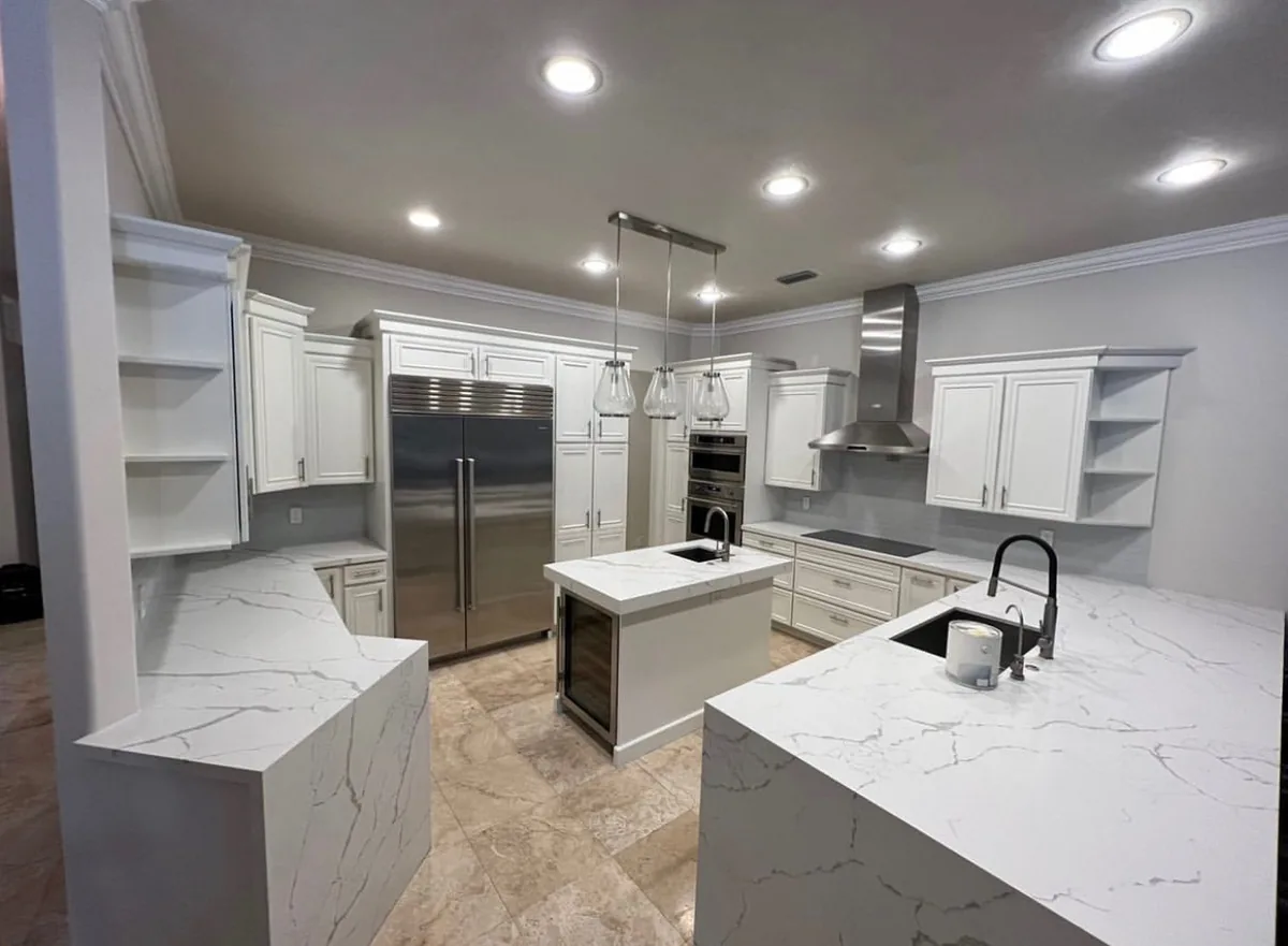 White raised panel kitchen with calacatta quartz waterfall island and stainless appliances
