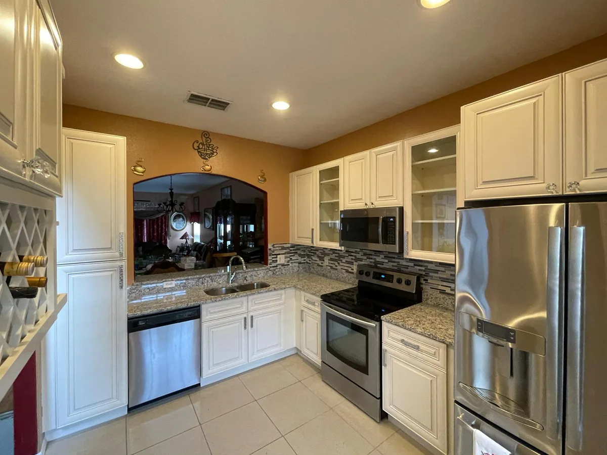 White raised panel kitchen with granite counters and a glass mosaic backsplash