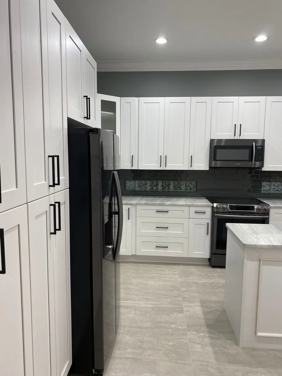 White shaker cabinets to the ceiling with black glass tile backsplash and gray quartzite counters