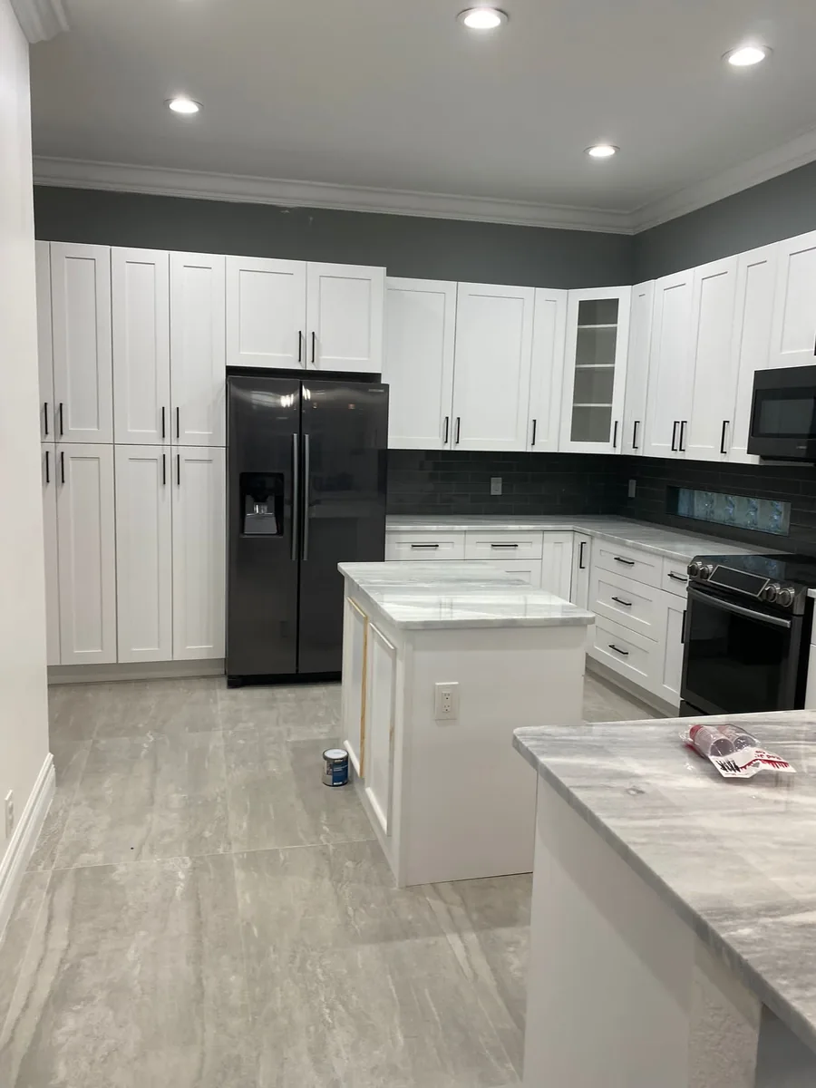 White shaker kitchen with a center island, black appliances and wood look tile floor
