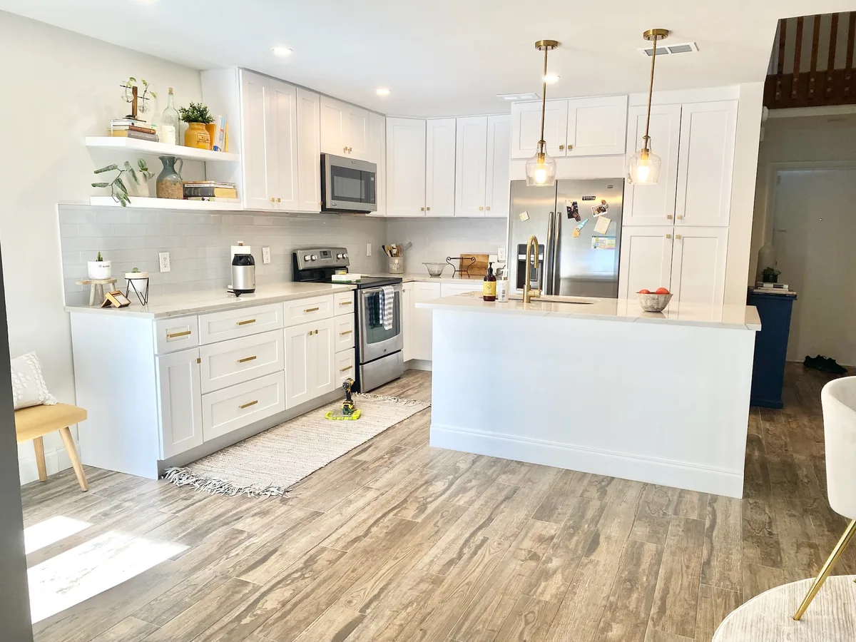 Bright white shaker kitchen with a large island, open shelves and brass pendant lights