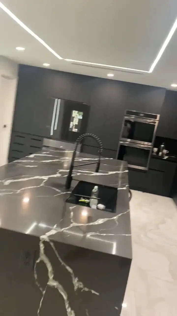 Short reel of five finished kitchens: charcoal with black quartz, dark gloss with waterfall island, white with black veined quartz, white shaker and gray with blue tile